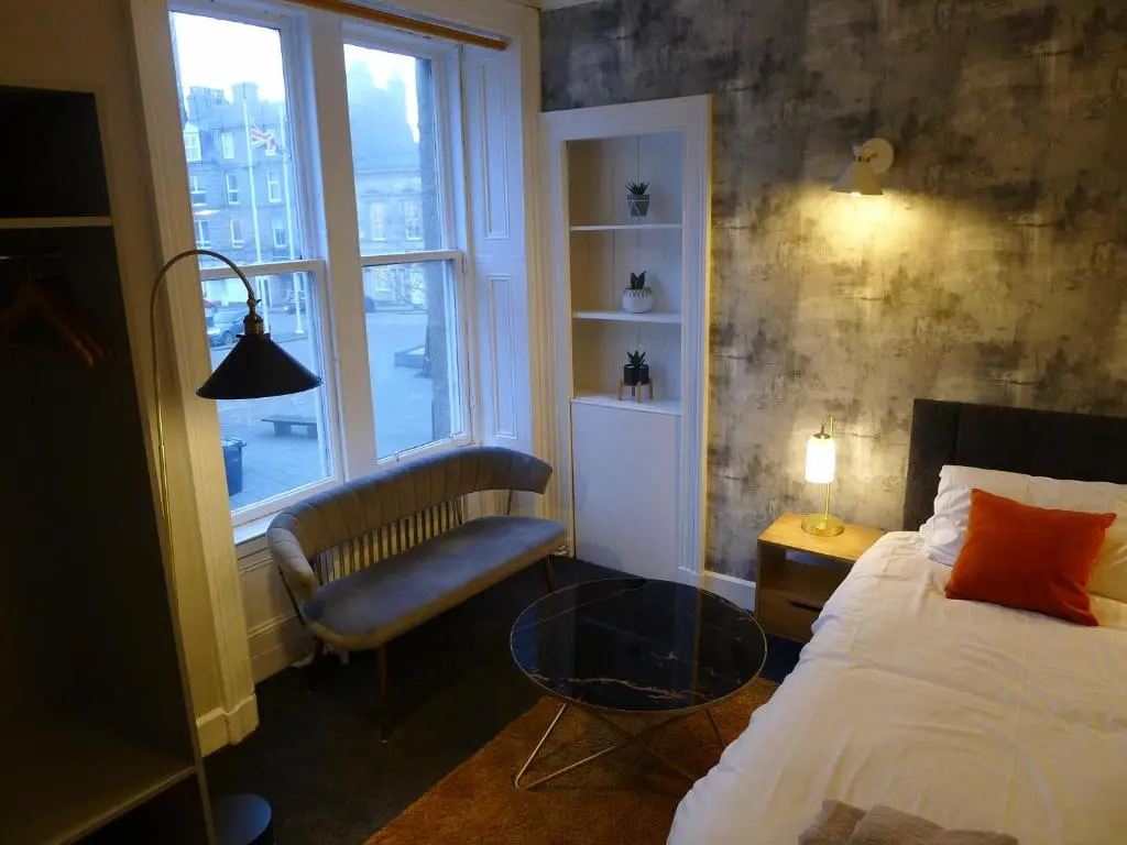 a bedroom with a bed and a chair and a window at Saltoun House in Fraserburgh
