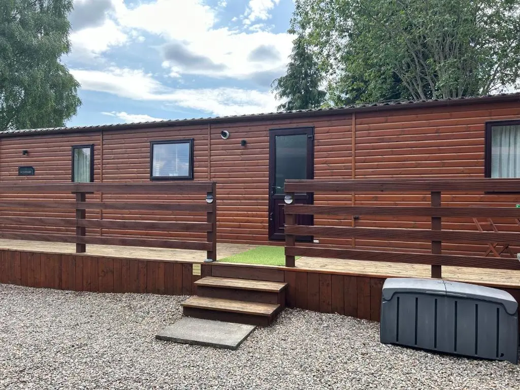 a wooden cabin with a bench and stairs in front of it at Lodge 2 The Wee Hut Aviemore in Aviemore