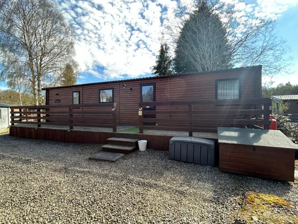a large wooden cabin with stairs and a house at Lodge 2 The Wee Hut Aviemore in Aviemore