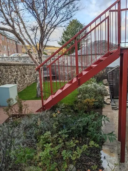 a red bridge in a garden with a tree at Top Floor Flat Ceol Na Mara (Music of the Sea) in Rosemarkie