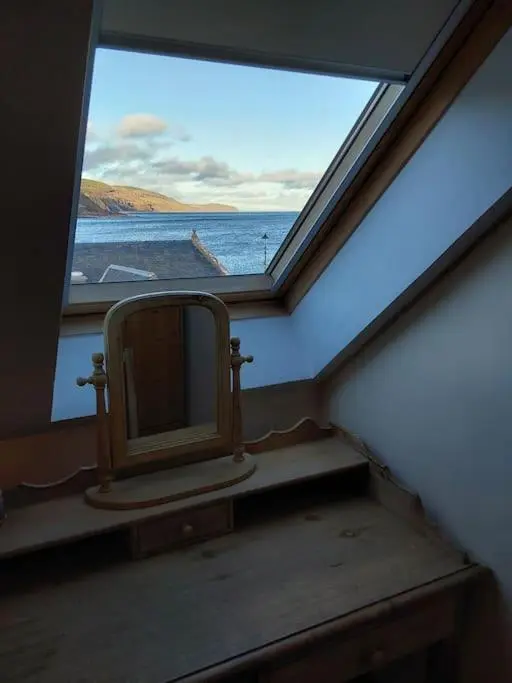 a bathroom with a window with a mirror in it at Top Floor Flat Ceol Na Mara (Music of the Sea) in Rosemarkie