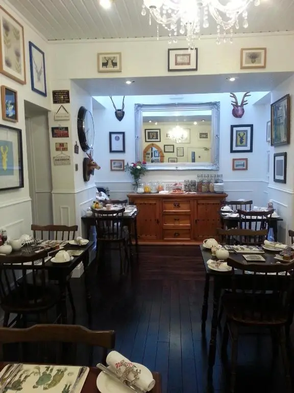 a restaurant with tables and chairs and a counter at Ardlogie Guest House in Aviemore