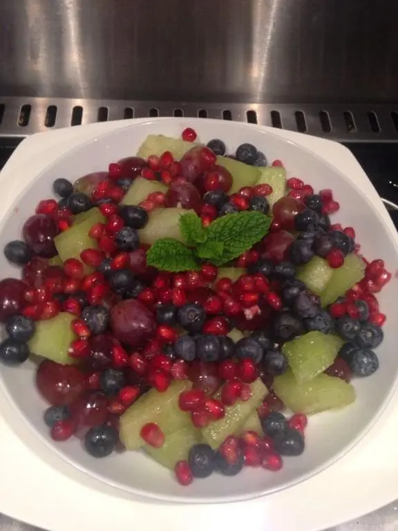 a plate of fruit with berries and a green leaf at Ardlogie Guest House in Aviemore