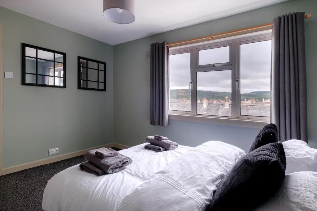 a person laying on a bed in a room with a window at Banchory House - SJA Stays - 2 Bed House in Banchory