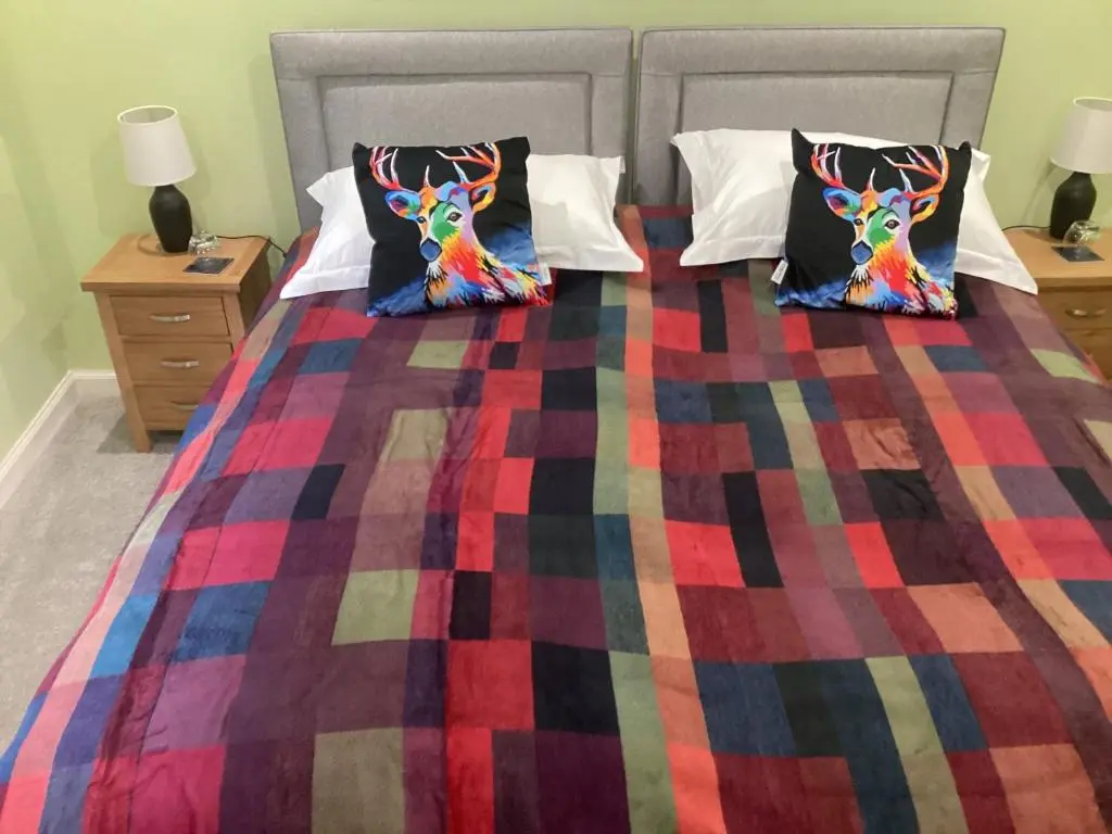 a bed with a colorful blanket and pillows on it at Taigh Sealladh F\u00e8idh B&B in Fort Augustus