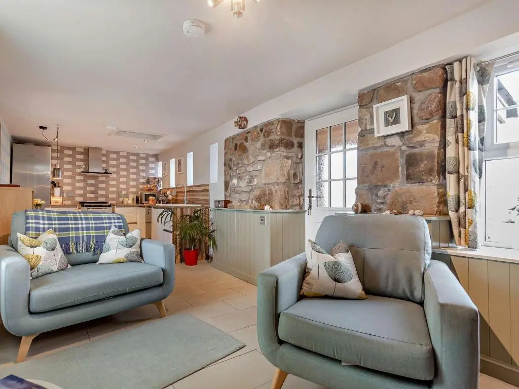 a living room with two chairs and a kitchen at 1 Bed in Elgin 32129 in Burghead