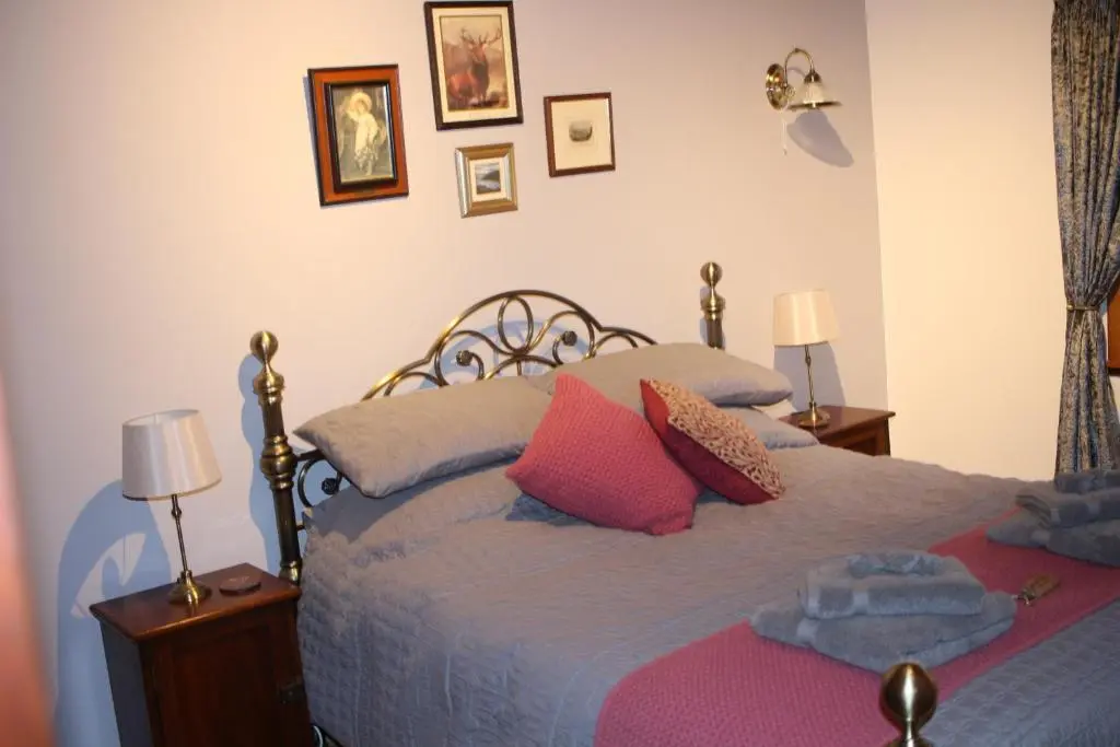 a bedroom with a bed with pink and gray pillows at Invercassley cottage in Lairg