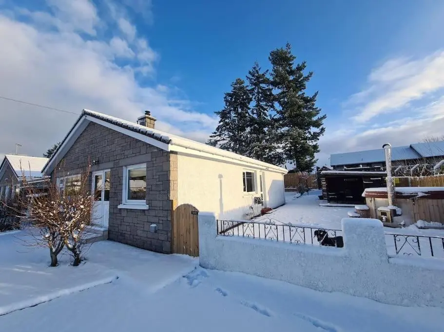 a small house in the snow in a yard at Town centre house, Hot tub, Cinema room and Gym in Aviemore