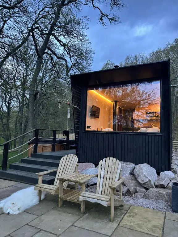 two chairs sitting next to a building with a large window at Dog friendly cabin & hot tub and Cairngorm views in Aviemore