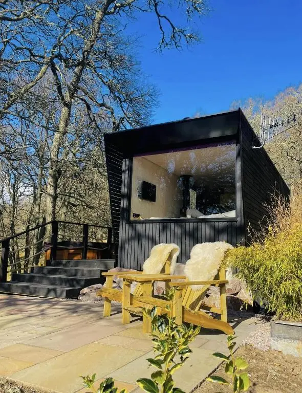 a couple of chairs and a bench in front of a building at Dog friendly cabin & hot tub and Cairngorm views in Aviemore