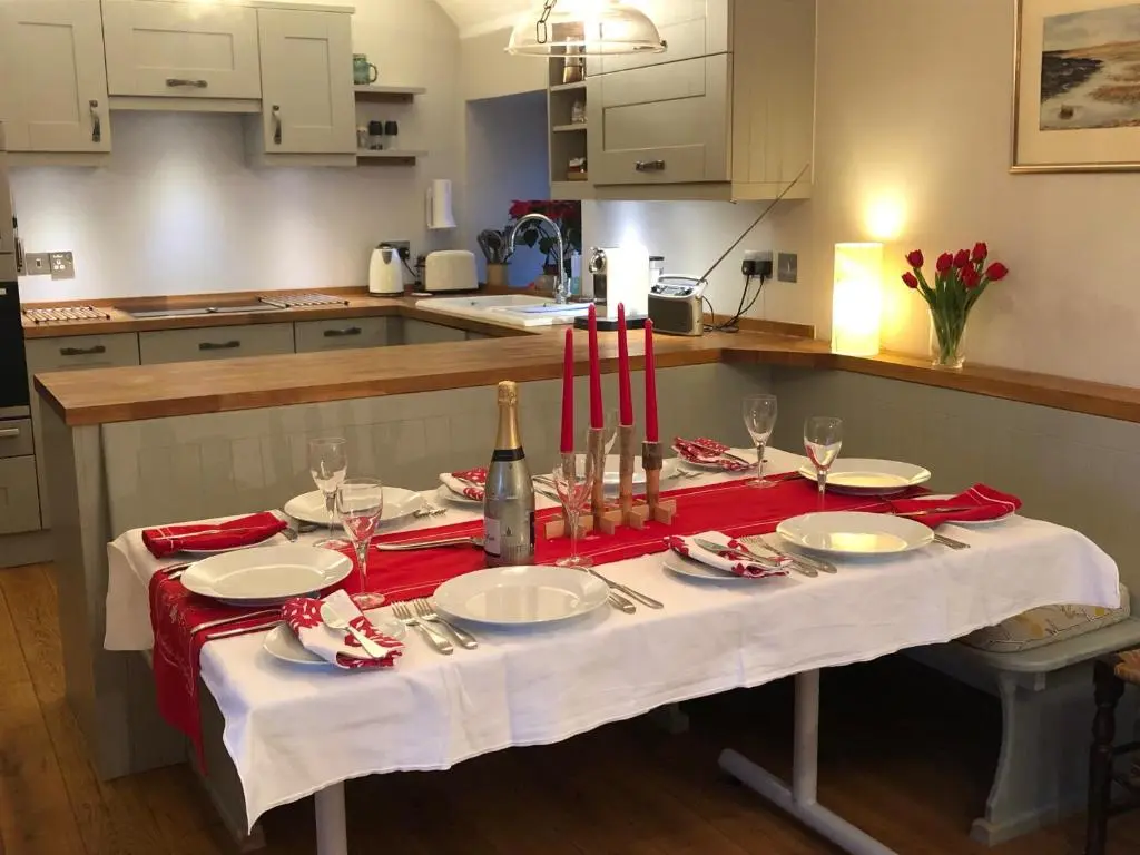 a table with plates and wine glasses on it in a kitchen at Drumguish Cottage in Kingussie