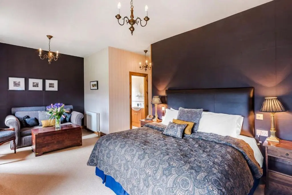 a large bedroom with a large bed and a chair at Caledonian Lodge in Croick