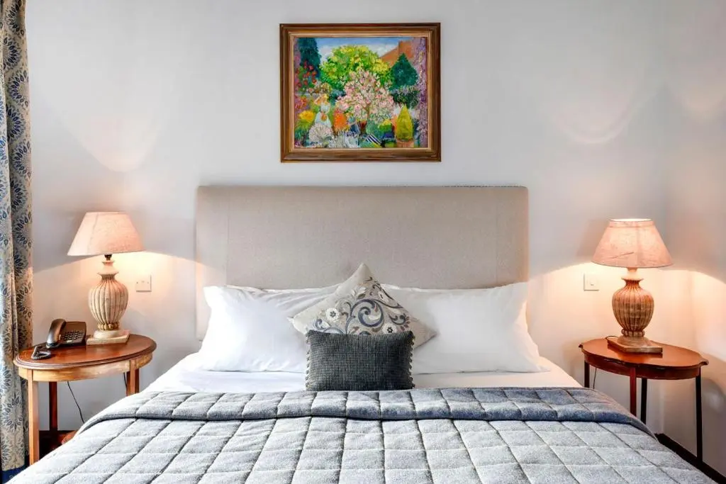 a bedroom with a bed with two lamps and a painting at Caledonian Lodge in Croick