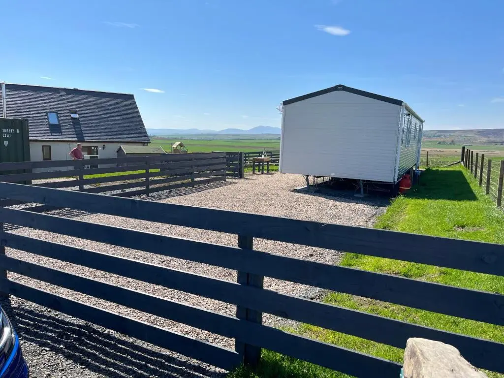 a small white shed sitting next to a fence at Robyn\u2019s Nest in Lybster