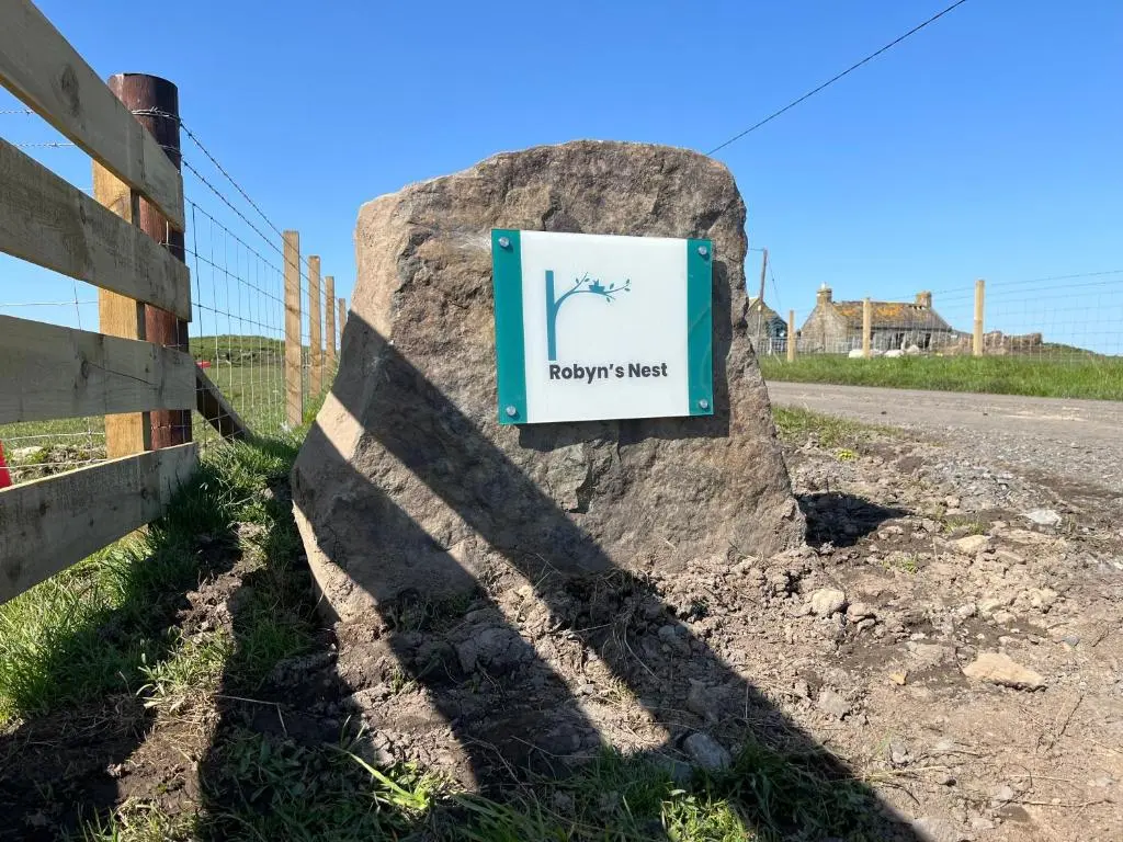 a sign on a rock next to a fence at Robyn\u2019s Nest in Lybster