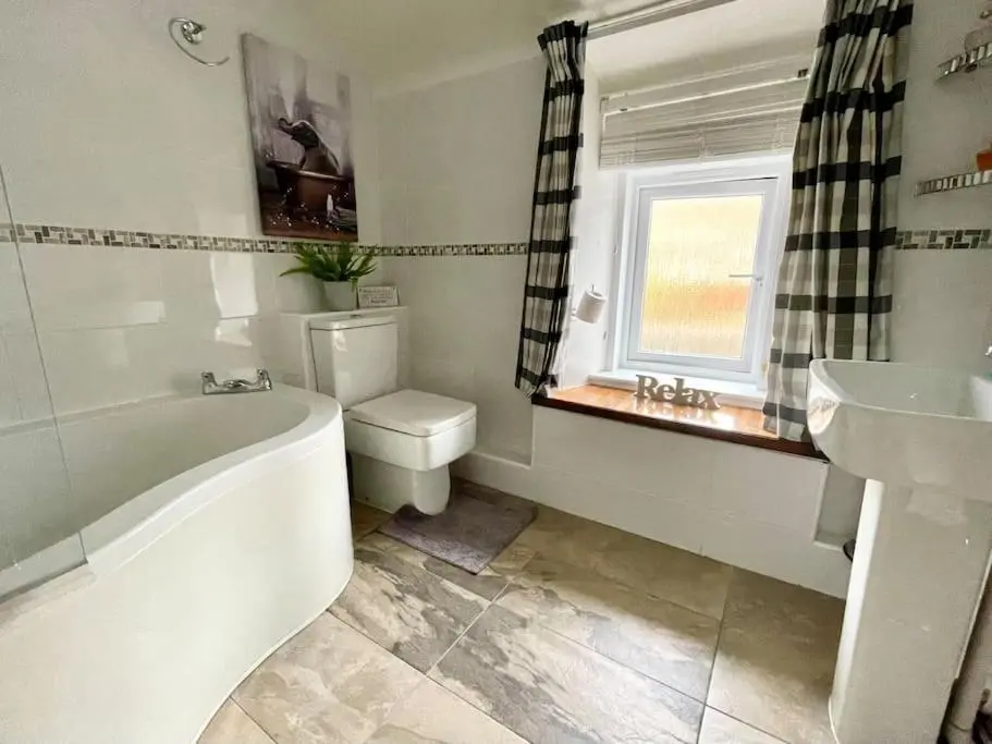 a bathroom with a tub and a toilet and a sink at Comfortable 4 bed Home, Valhalla, Helmsdale in Helmsdale