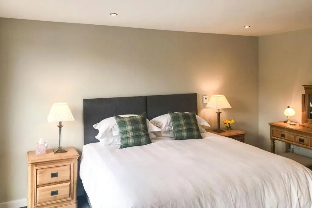 a bedroom with a bed with two night stands and two lamps at Greenhill Cottage in Evanton