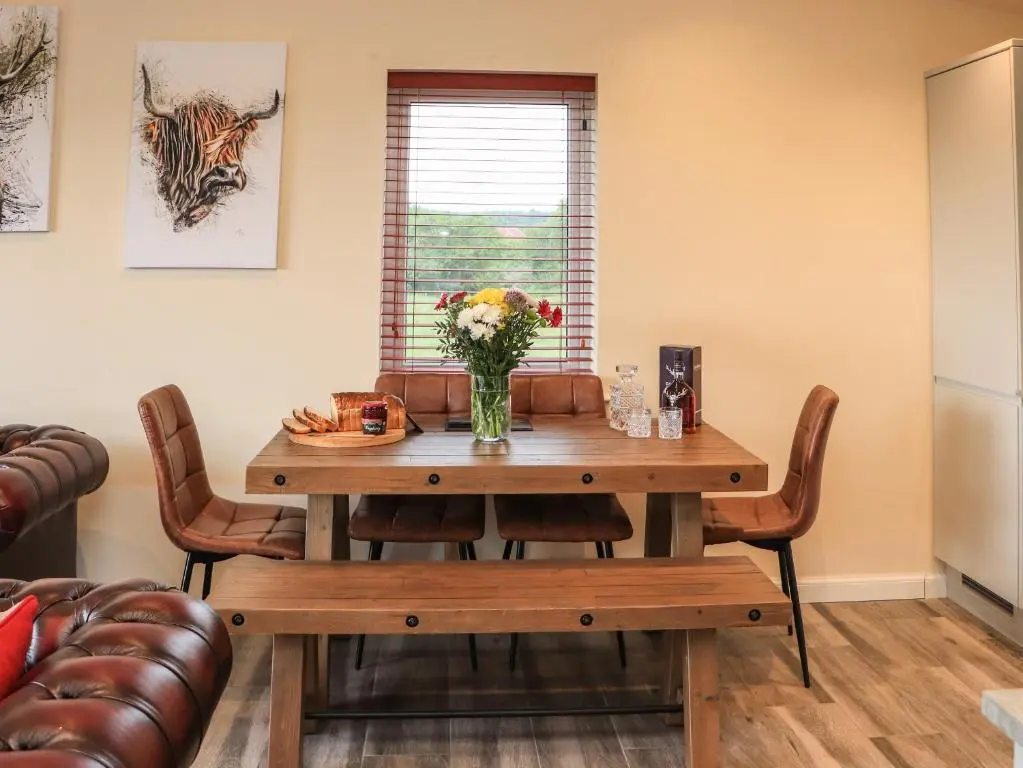 a dining room table with a vase of flowers on it at Pine Marten in Dornoch