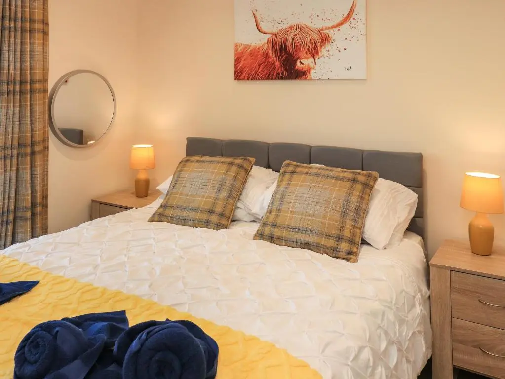 a bedroom with a bed with a cow on the wall at Pine Marten in Dornoch