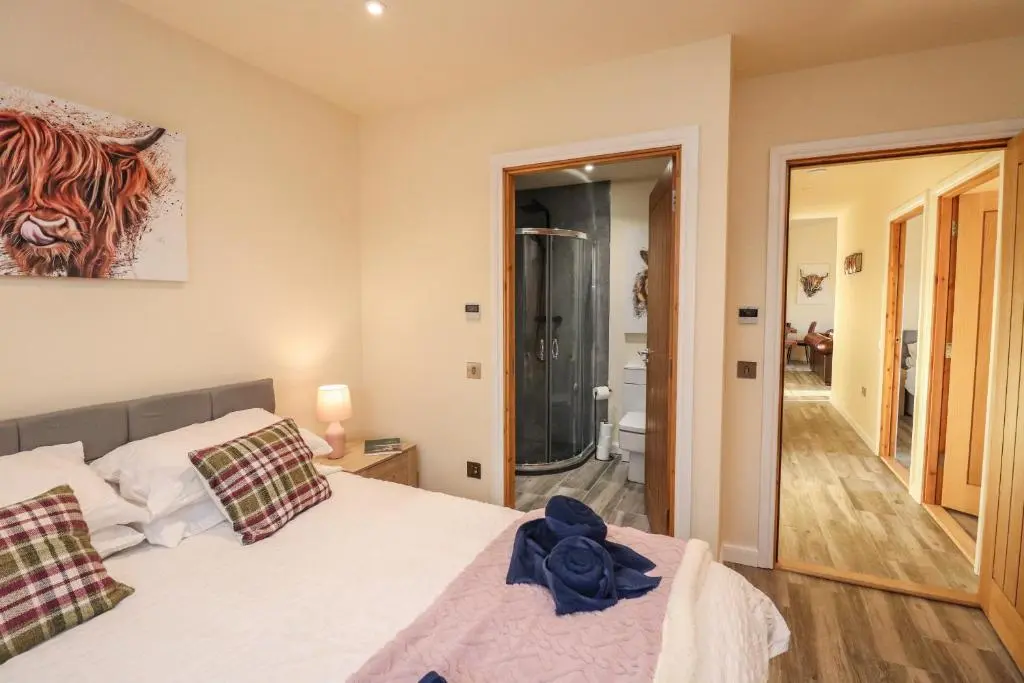 a bedroom with a bed and a walk in shower at Red Squirrel in Dornoch