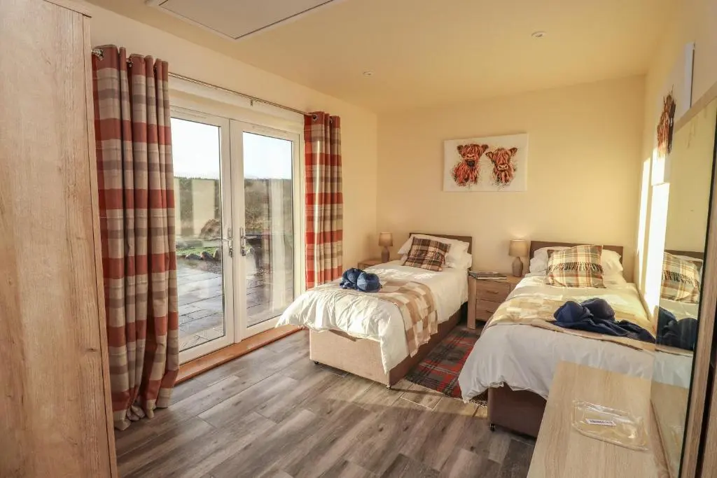 two beds in a room with a window at Red Squirrel in Dornoch