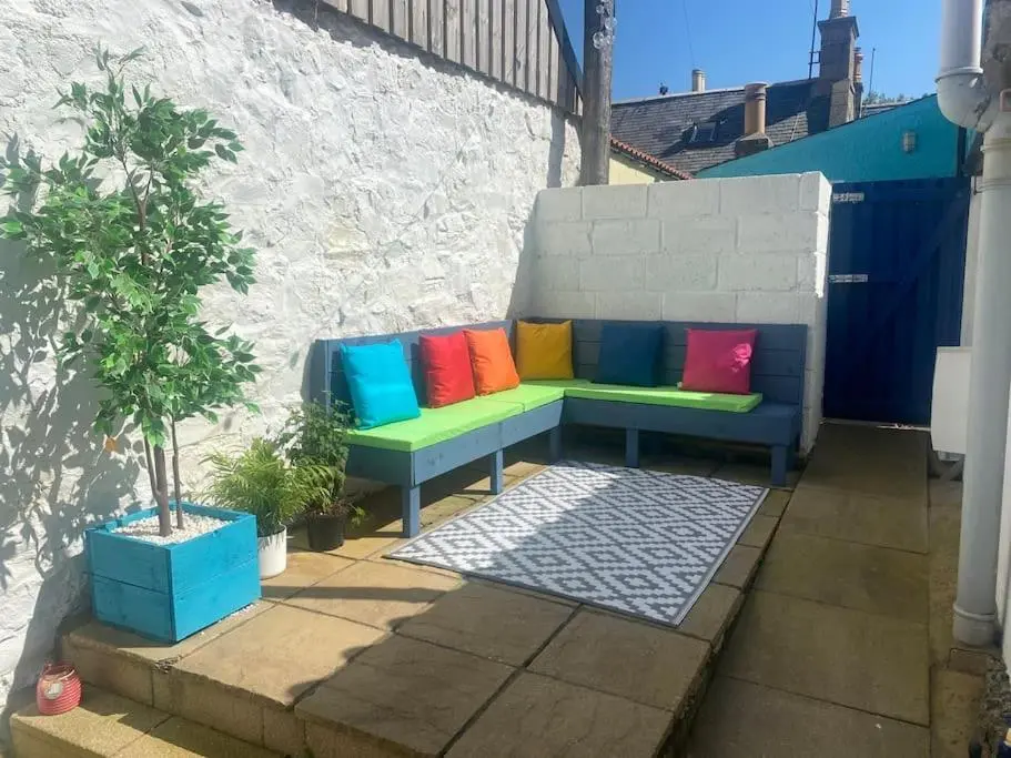 a bench with colorful pillows sitting next to a wall at Cullen Seaside Cottage in Cullen