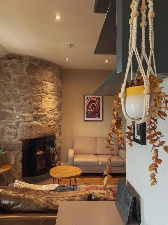 a living room with a couch and a stone fireplace at Unique Highland in Inverness