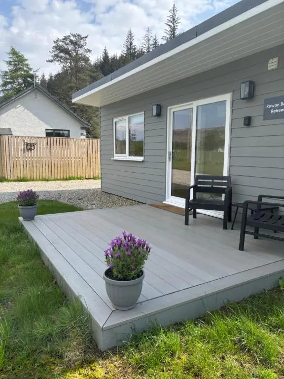 a porch with a bench and flowers on a house at Rowan Bank Retreat in Fort Augustus