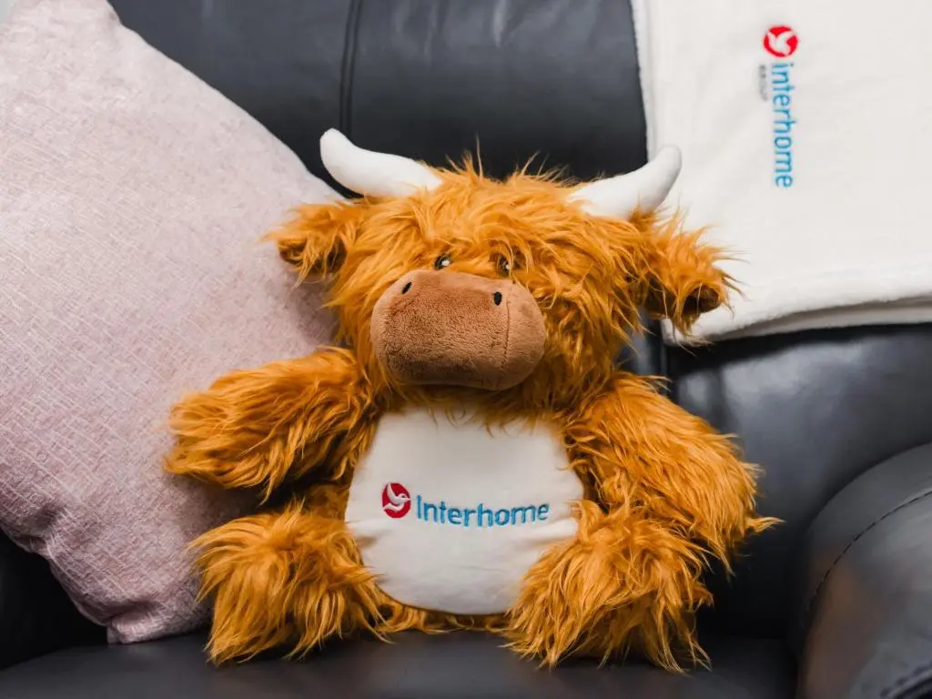 a teddy bear sitting on a couch with a pillow at Apartment Number 39 by Interhome in Inverness