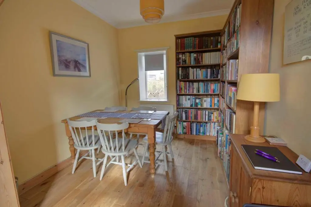 a dining room with a table and some bookshelves at Crossing Cottage, Brora in Brora