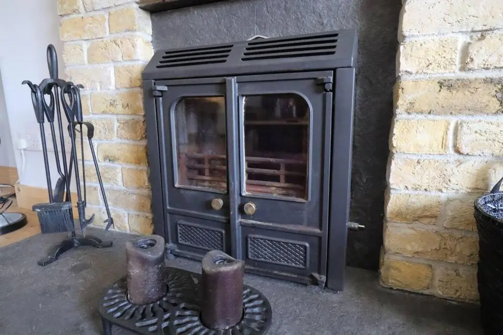 an old black stove sitting next to a brick wall at Crossing Cottage, Brora in Brora