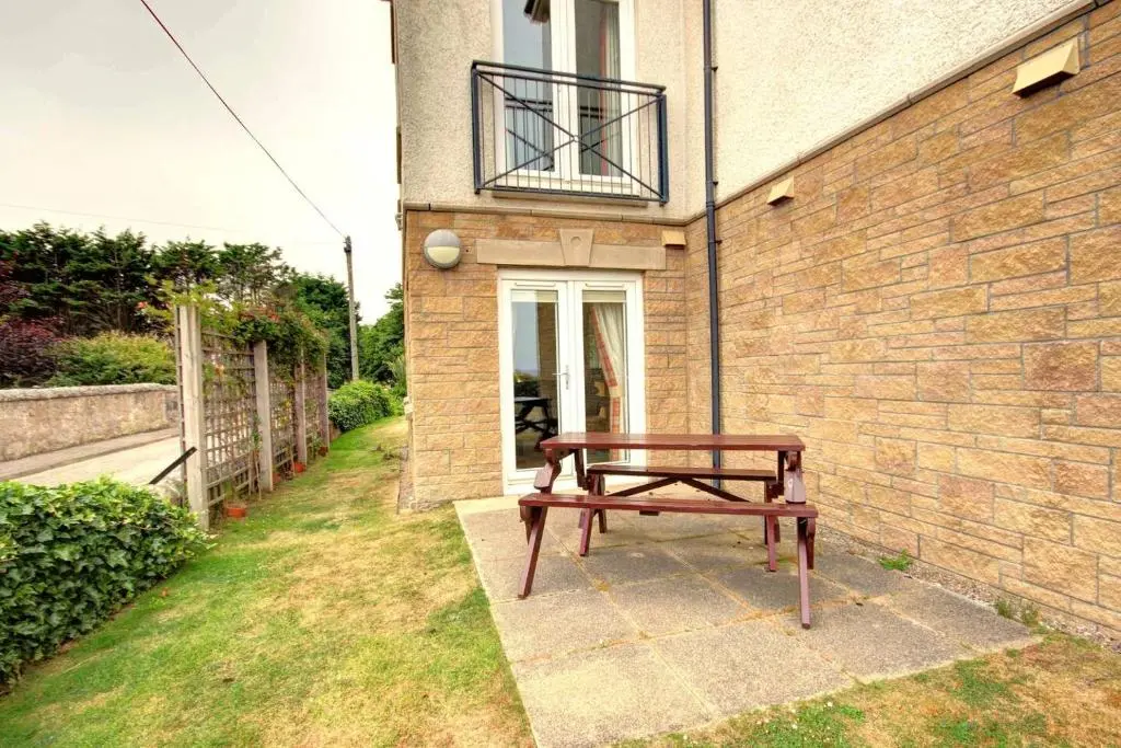 a wooden bench sitting in front of a building at No1 The Links Apartment, Brora in Brora