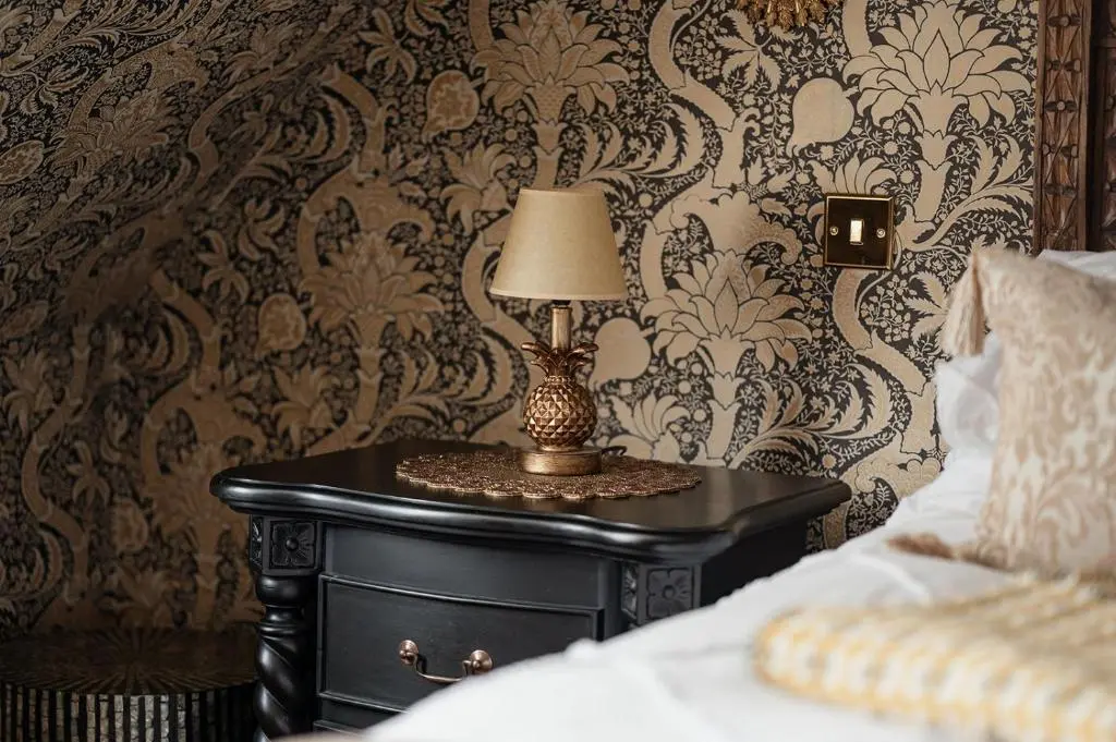 a table with a lamp on it next to a bed at Luxury 3 Bedroom Cottage - Sleeps 6 in Tomintoul