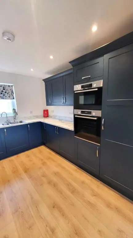 a kitchen with navy blue cabinets and a wooden floor at Insch House in Kincraig