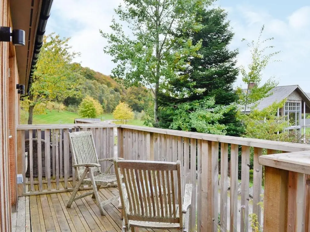 two chairs on a deck with a fence at Ness Castle Lodges in Inverness