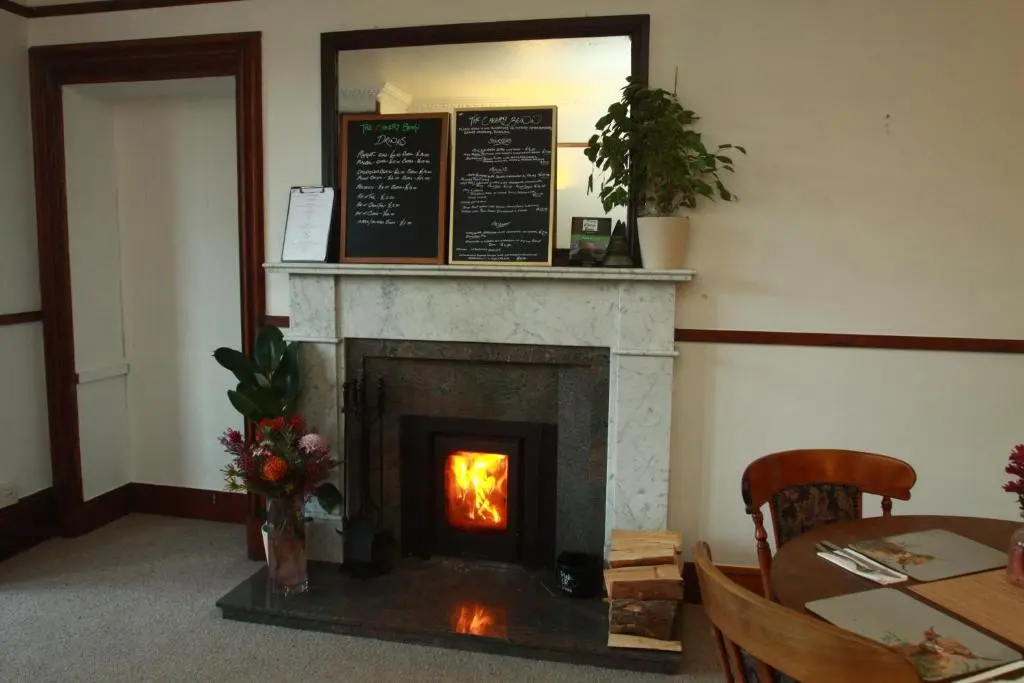 a fireplace in a room with a table and a mirror at The Retreat Hotel in Strathpeffer