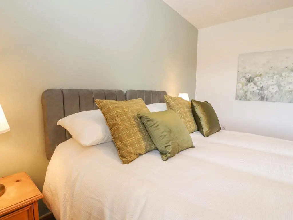 a bedroom with a large white bed with pillows at Reyflat Barn in Fortrose