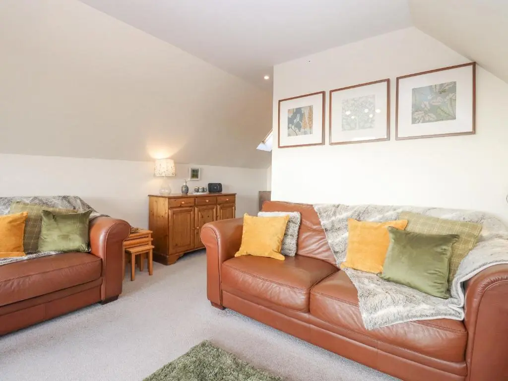 a living room with two brown leather couches at Reyflat Barn in Fortrose