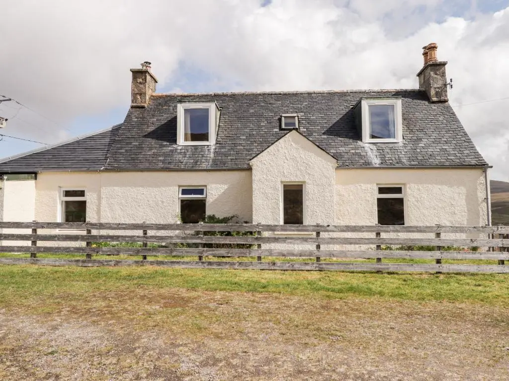 an old house with a fence in front of it at Loubcroy Farm House in Lairg