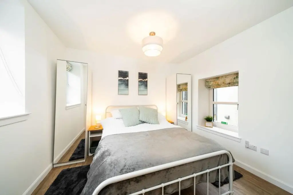a bedroom with a bed and two windows at The Corner House in Hopeman