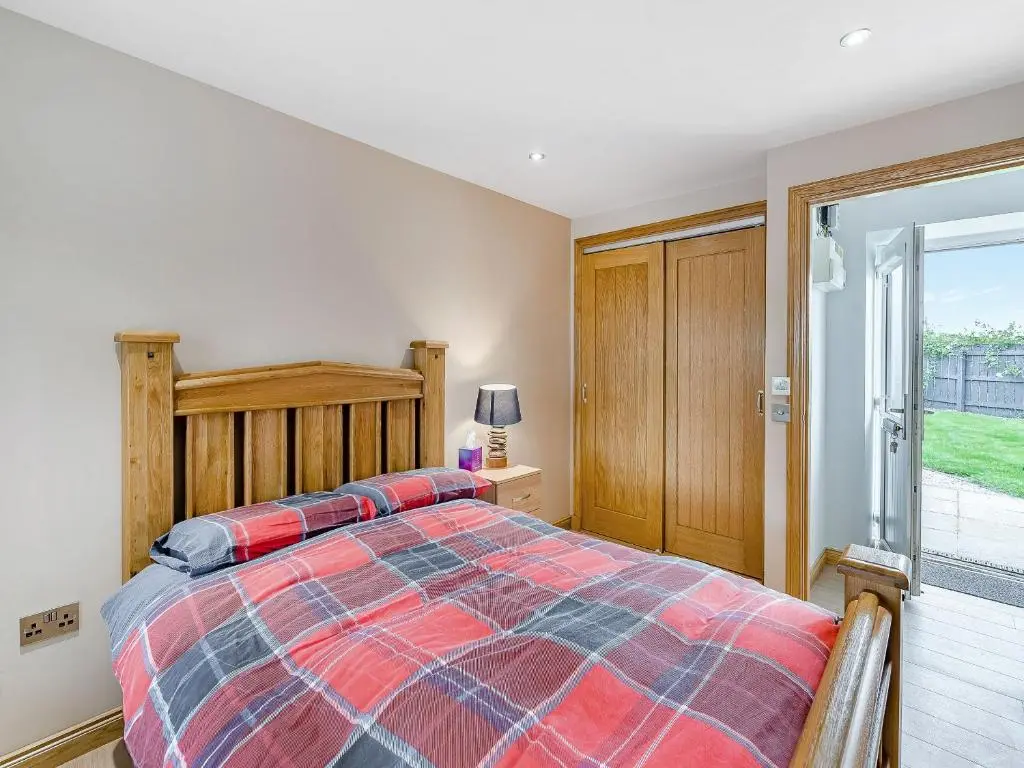 a bedroom with a bed and a sliding glass door at Mains Of Durn Cottage, in Banff