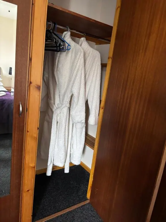 a closet with white clothes hanging in it at Cameron apartment Loch Ness in Fort Augustus