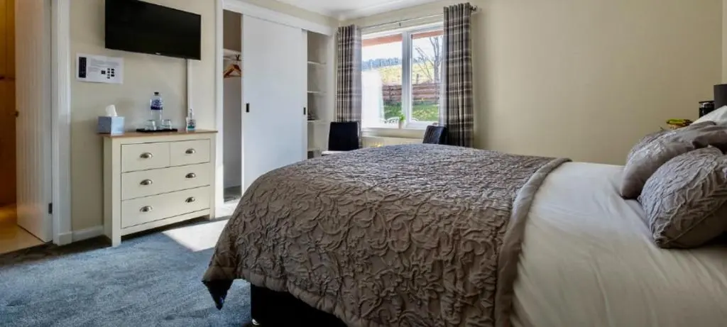 a bedroom with a bed and a dresser with a television at Eldon Lea in Strathpeffer