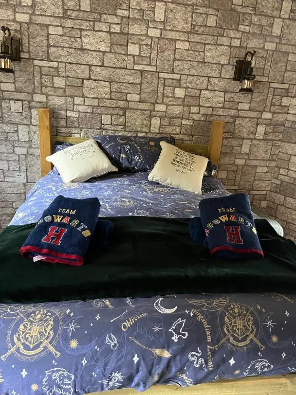 a bed with pillows on it next to a brick wall at Hagrids Hut - Off grid Cabin - no electricity or running water in Munlochy