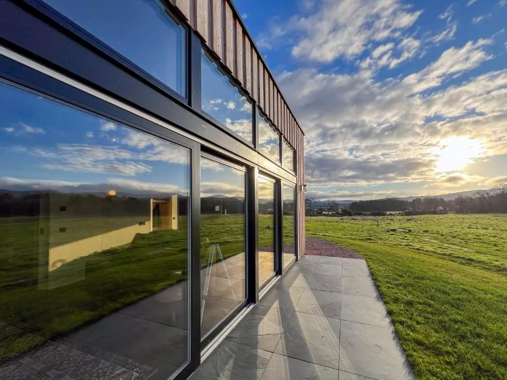 a glass building with a view of a field at Tillyfruskie Farm Holiday Cabin, Finzean in Banchory