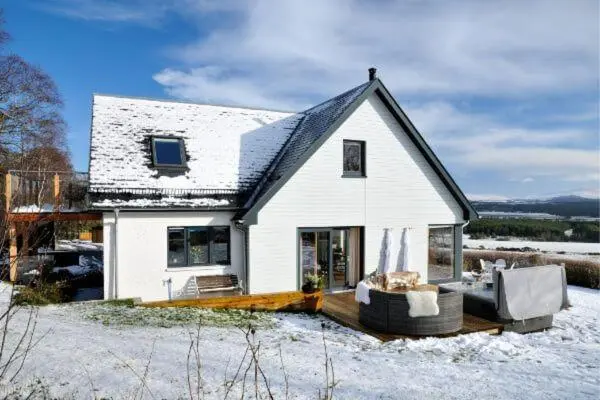 a white house with snow on the ground at Beautiful Lodge with hot tub & panoramic views in Boat of Garten