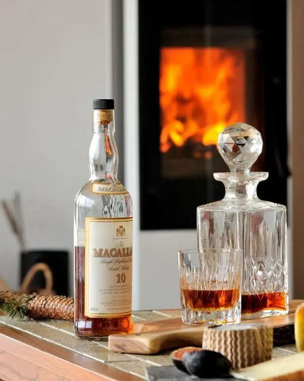 a bottle of alcohol next to a glass of whiskey at Beautiful Lodge with hot tub & panoramic views in Boat of Garten