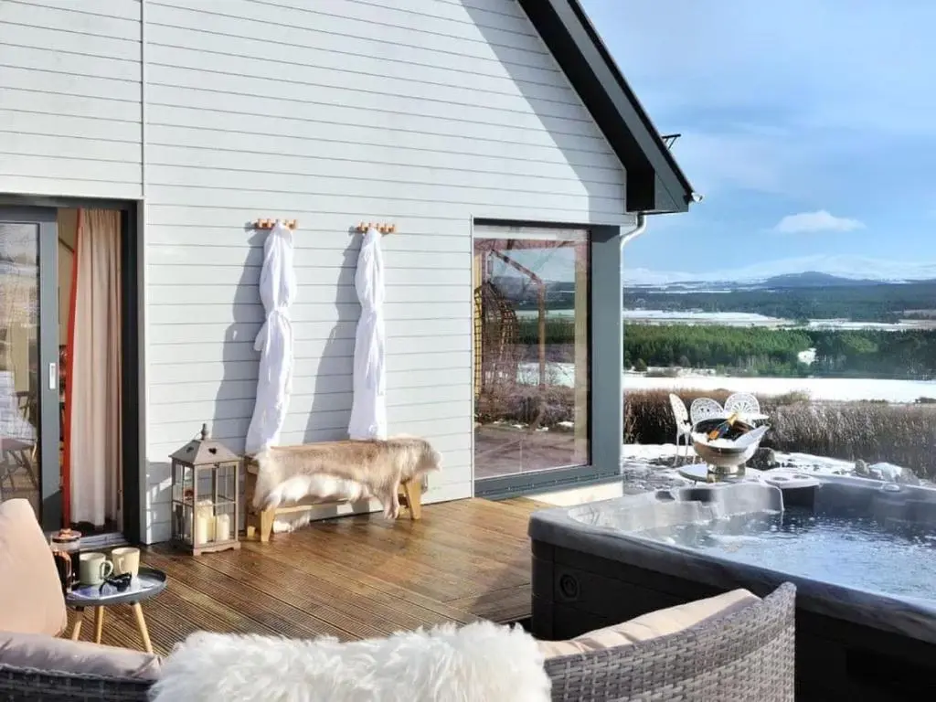 a dog standing on the deck of a house at Beautiful Lodge with hot tub & panoramic views in Boat of Garten