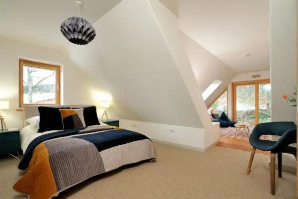 a bedroom with a bed and a chair in a room at Beautiful Lodge with hot tub & panoramic views in Boat of Garten