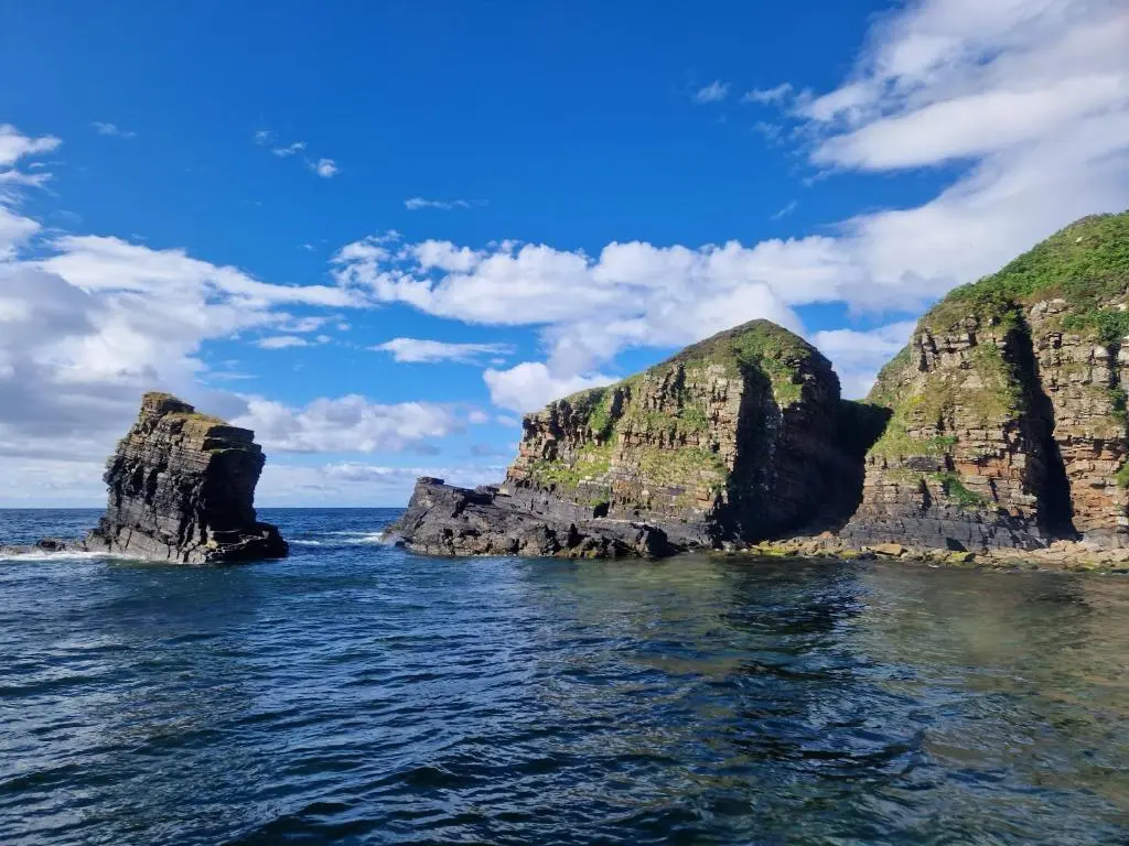 two large rocks in the ocean on a sunny day at Byrnside Lodge in Latheron